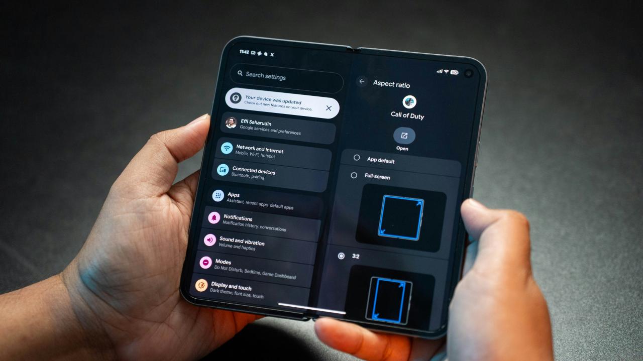 Tangan memegang smartphone lipat menampilkan menu pengaturan