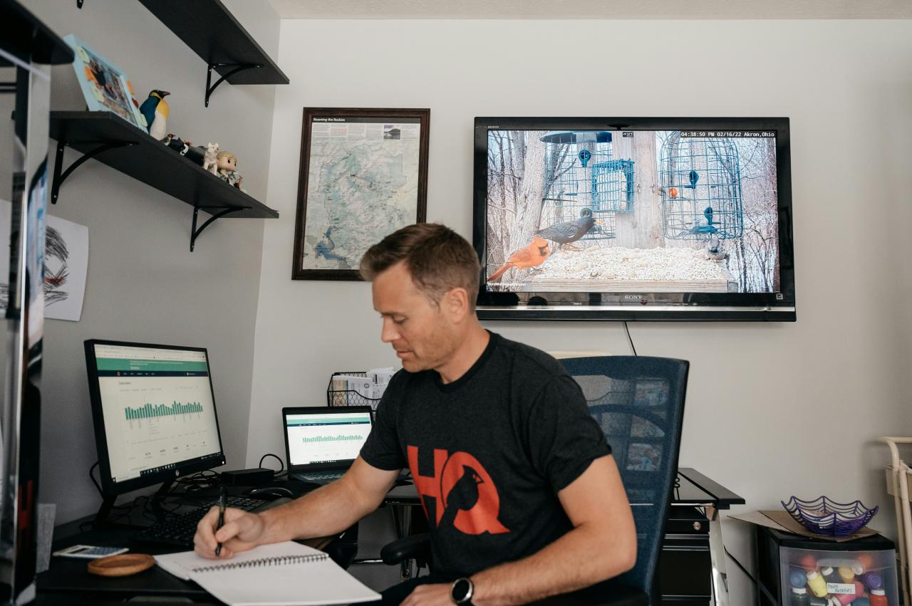 seorang pria duduk di meja dengan komputer dan monitor