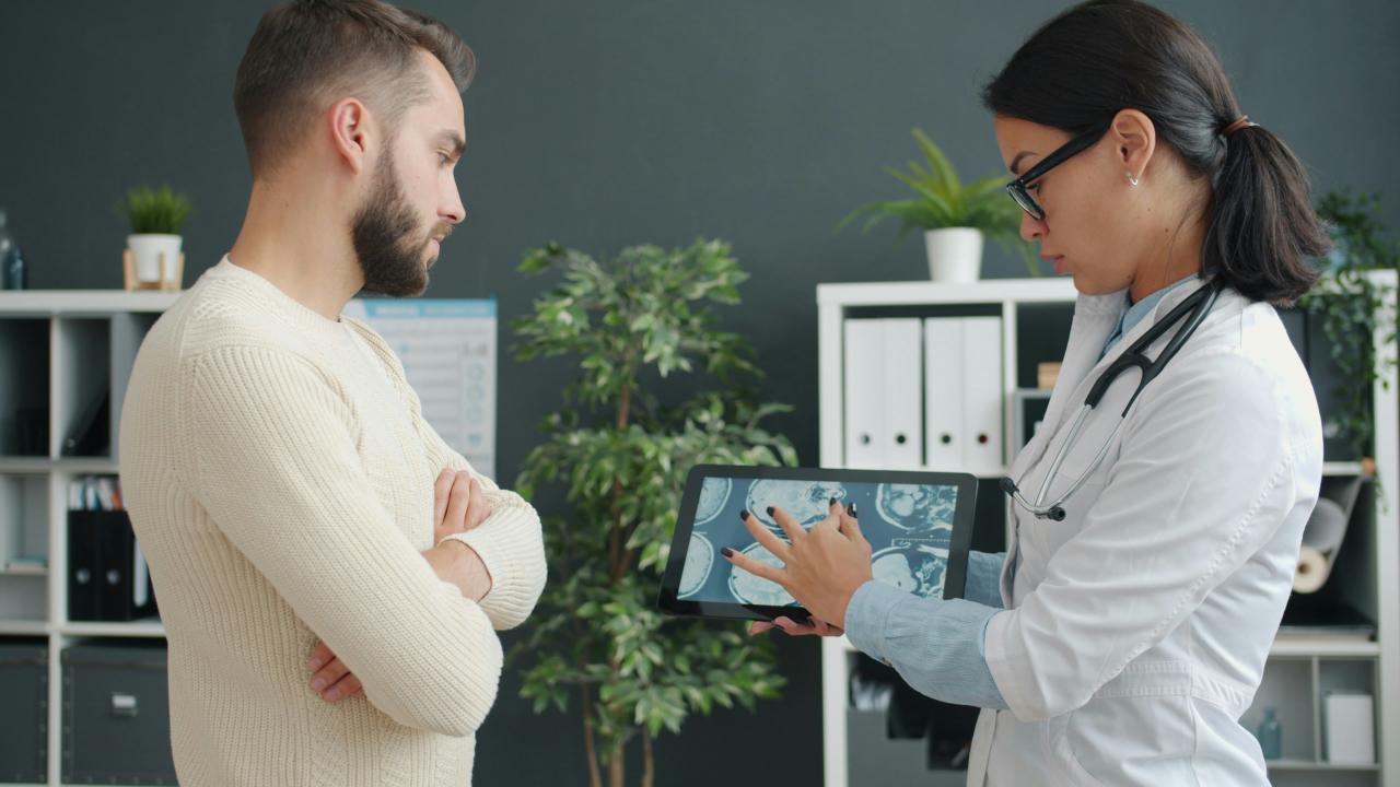 Dokter menunjukkan pemindaian medis pasien pada tablet.